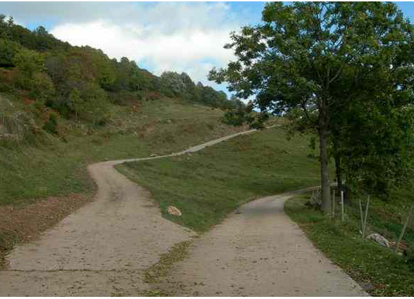Photo d'un carrefour avec un chemin plus troit qui monte  gauche et un autre plus large  droite